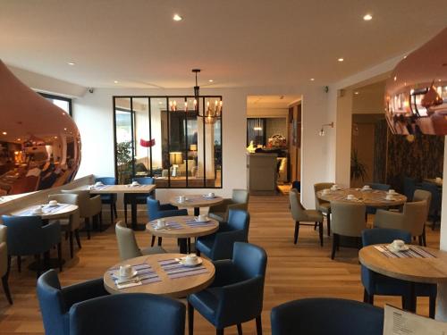 a restaurant with wooden tables and chairs and a cafeteria at Le Galion Hotel et Restaurant Canet Plage - Logis in Canet-en-Roussillon