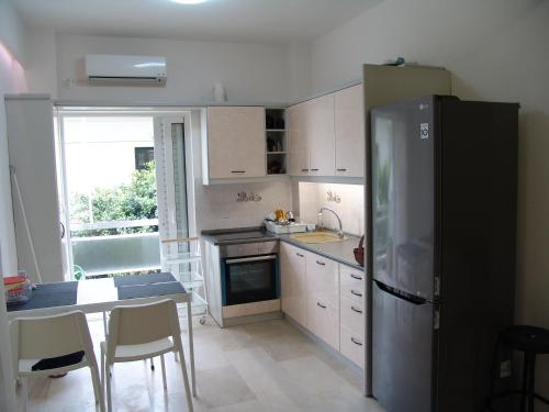 een keuken met een koelkast en een tafel met stoelen bij Grace Apartments in Loutraki