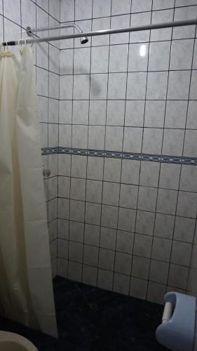 y baño con ducha de azulejos blancos y aseo. en Tour Hostal Wanka, en Huancayo