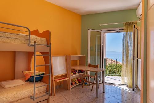 1 Schlafzimmer mit Etagenbetten, einem Schreibtisch und einem Balkon in der Unterkunft Ioannis House Sea View in Lourdata