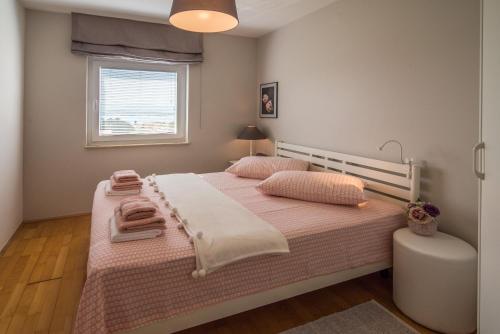 a bedroom with a bed with pink sheets and a window at Apartment Luna in Malinska