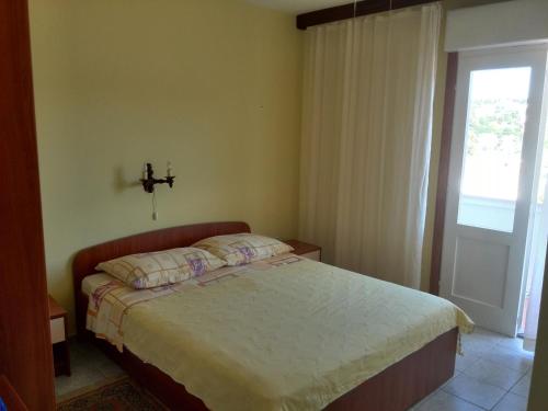 a bedroom with a bed and a window at Kampor Apartments in Kampor