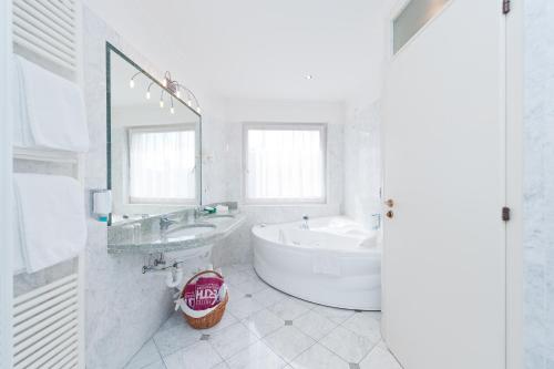 a white bathroom with a tub and a sink at Business Resort Parkhotel Werth in Bolzano