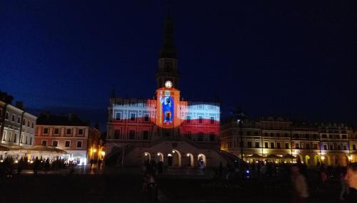 a building lit up in red and blue at night at Pokoje Stare Miasto in Zamość