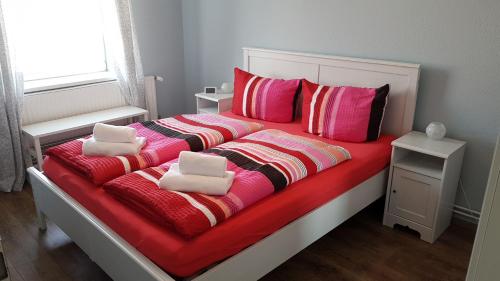 ein Bett mit roten und rosa Decken und Kissen in der Unterkunft PEMATRA Ferienwohnung Fährblick in Travemünde