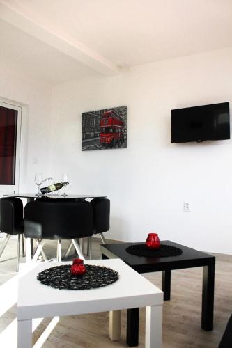 a living room with a table and a tv on the wall at JK apartmani in Herceg-Novi