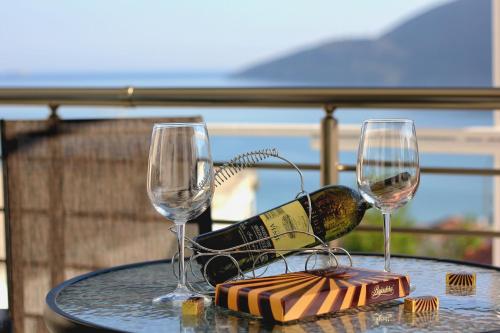 a table with two glasses and a bottle of wine at JK apartmani in Herceg-Novi
