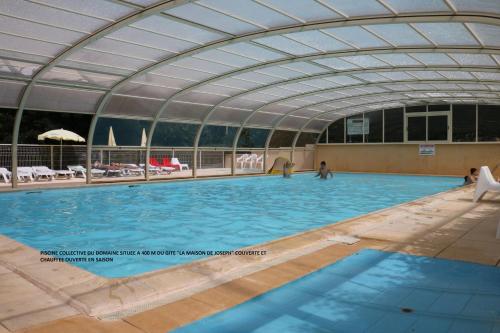 une grande piscine intérieure avec un plafond voûté dans l'établissement Gites Domaine du Charouzech, à Salles-Curan