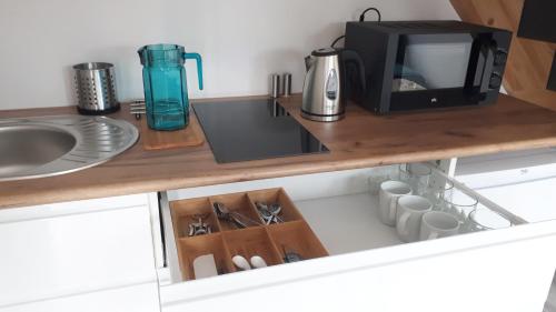 a kitchen counter with a microwave and a sink at Pueblo Apartamenty in Stegna