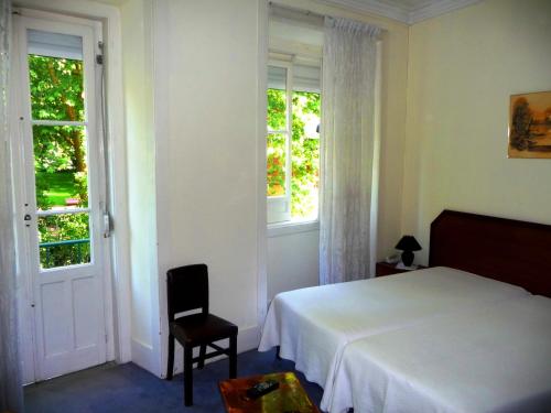 a bedroom with a bed and a chair and windows at D. Carlos Residencial in Caldas da Rainha