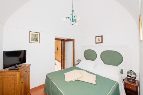 a bedroom with a bed with a green headboard and a television at Casa Chiesa Nuova in Positano