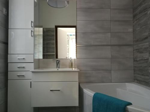 a bathroom with a sink and a tub and a mirror at Class Apartment in Szeged
