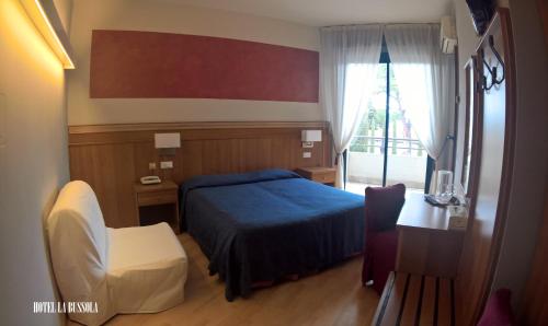 a bedroom with a blue bed and a desk and a window at Hotel La Bussola in Padenghe sul Garda