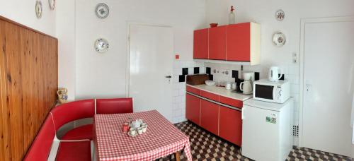 een kleine keuken met rode kasten en een rode tafel en stoel bij Julius Vendégház in Sopron