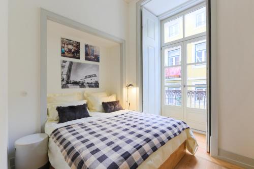 1 dormitorio con 1 cama a cuadros y 2 almohadas en Bacalhoeiros 99 - Beautiful and bright Apartment @ Baixa, Chiado, en Lisboa