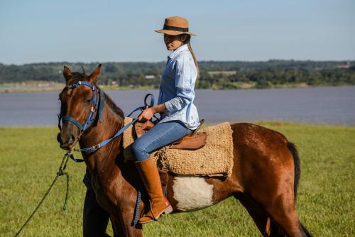 a woman riding on a horse in a field at Awa Resort Hotel in Encarnación