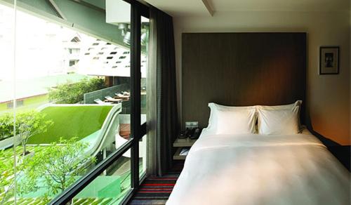 a bedroom with a bed and a large window at LiT BANGKOK Hotel in Bangkok