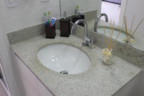 a bathroom counter with a sink with toothbrushes at O local para o seu lazer in Santos