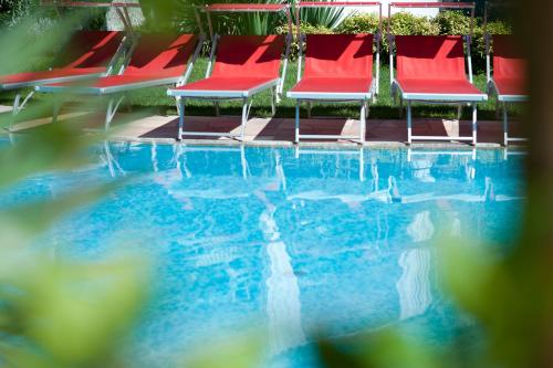 a group of red chairs sitting next to a swimming pool at Business Resort Parkhotel Werth in Bolzano