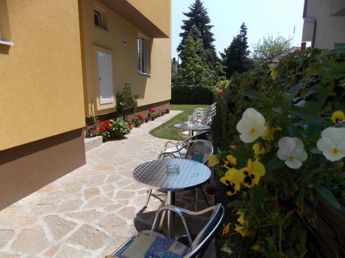 a patio with three tables and chairs and flowers at Sobe i apartmani Kety in Kragujevac