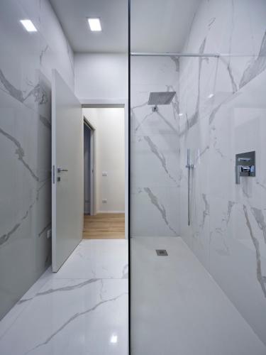 a bathroom with white marble walls and a corridor at Suite Vogue Espresso in Voghera