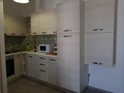 a kitchen with white cabinets and a microwave at Giuly home two in Càbras