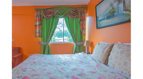 a bedroom with a bed and a window with green curtains at Sundreamer Suite @ Turtle Towers in Ocho Rios
