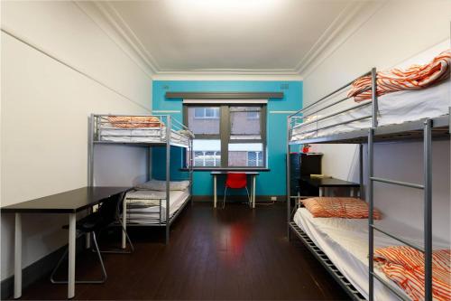 um quarto com 3 beliches e uma secretária em South Yarra Hostel em Melbourne