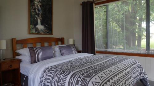 a bedroom with a bed and a large window at Templenoe Paradise in Te Anau