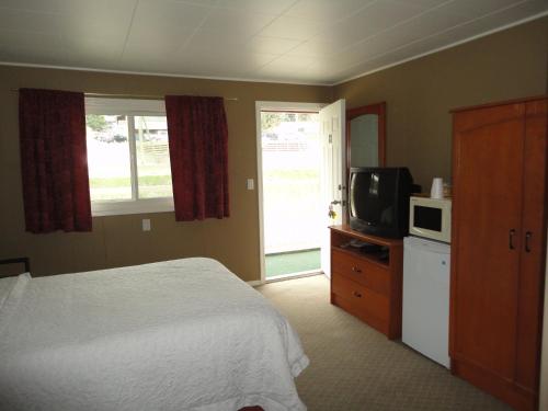 a bedroom with a bed and a microwave and a television at Sorrento Inn Motel in Sorrento