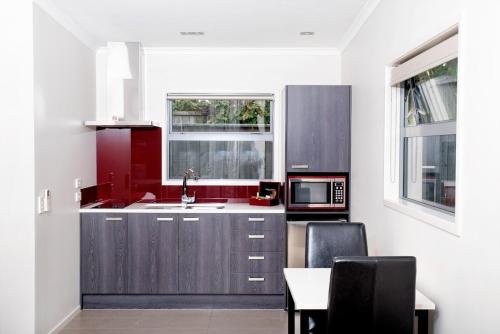 a kitchen with red and white cabinets and a table at 37 The Landing Motel in Whakatane