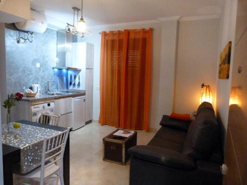 アンテケラにあるNajera Suiteのリビングルーム(ソファ付)、キッチン(オレンジ色のカーテン付)