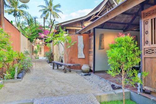 a courtyard of a house with a bench and trees at Apalagi Villas in Gili Air