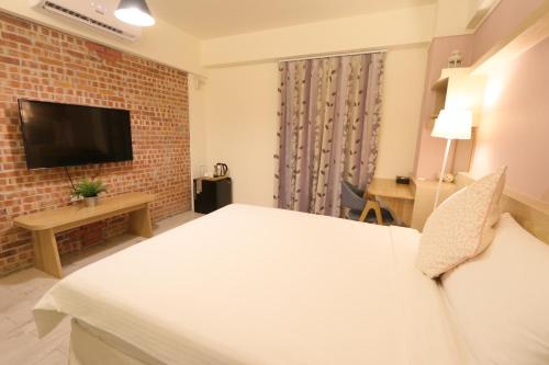 a hotel room with a bed and a tv at Flora Inn in Tainan