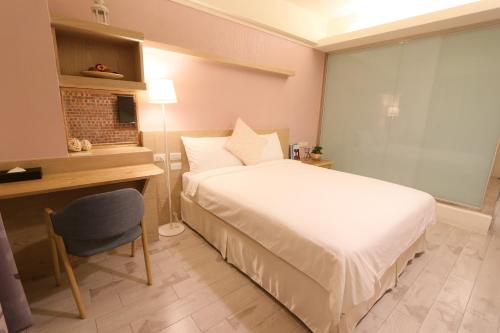 a bedroom with a bed and a desk and a chair at Flora Inn in Tainan