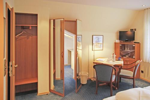 een hotelkamer met een tafel en een spiegel bij Haus Thorwarth - Hotel garni in Cuxhaven