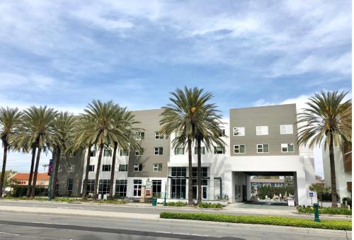 a building with palm trees in front of a street at Wyndham Anaheim in Anaheim