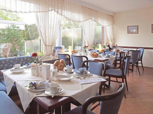 a dining room with tables and chairs and windows at Haus Thorwarth - Hotel garni in Cuxhaven