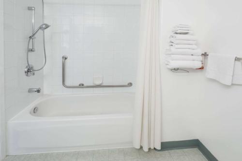 y baño blanco con bañera y toallas. en Super 8 by Wyndham Three Hills AB, en Three Hills