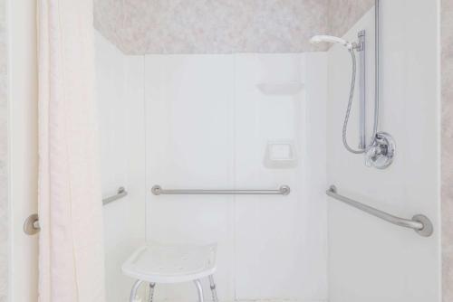 a shower with a white shower curtain and a stool at Microtel Inn & Suites by Wyndham Philadelphia Airport in Philadelphia