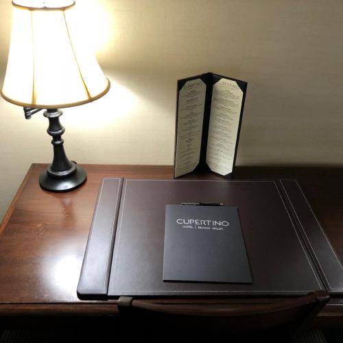 a laptop on a table with a lamp and a book at Cupertino Hotel in Cupertino