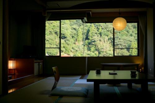 a living room with a table and a large window at Ichinomata Onsen Kanko Hotel in Shimonoseki