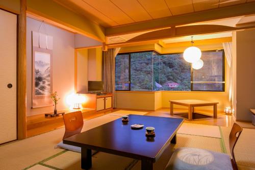 ein Wohnzimmer mit einem Tisch und einem großen Fenster in der Unterkunft Ichinomata Onsen Kanko Hotel in Shimonoseki