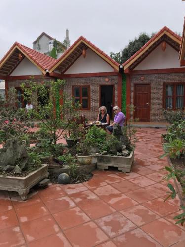 two people sitting at a table in a garden at Tam Coc Cozy Homestay in Ninh Binh