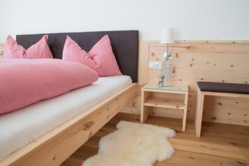 een slaapkamer met een bed met roze kussens en een tafel bij Tschott Hof in Villandro