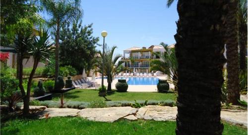 a house with a swimming pool and a palm tree at Garden Apartment Quinta do Morgado in Tavira