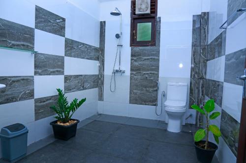 a bathroom with a shower and a toilet and plants at Kottamba Yala Stay & Safari in Tissamaharama