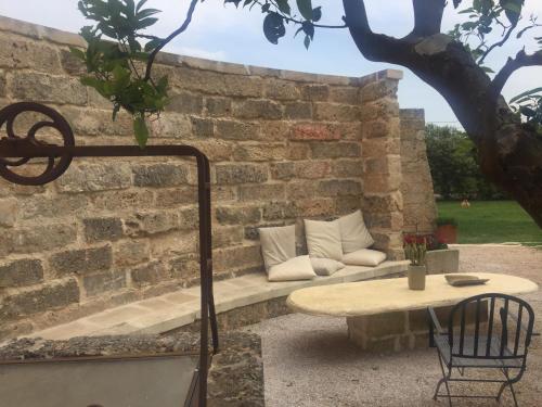 a stone wall with a bench and a table at Tenuta Monaci La Murra in Carmiano