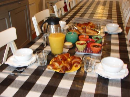 - une table avec petit-déjeuner composé de croissants et de jus d'orange dans l'établissement La Bruyère - chez Martine, à Appy