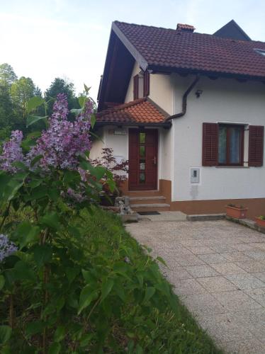 a white house with a red door and some purple flowers at Apartment Sela in Tolmin